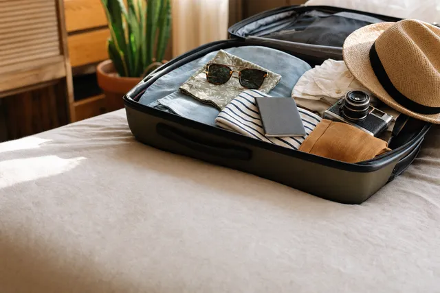 An open suitcase, packed, on a bed.