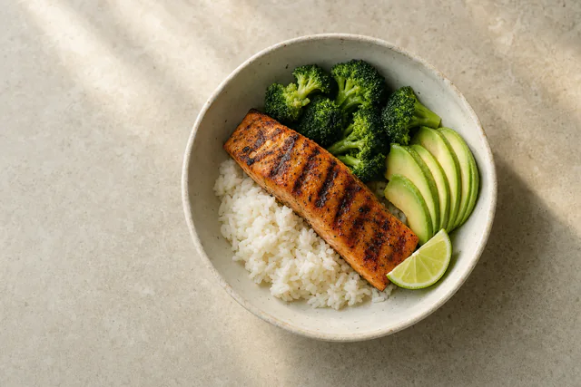 A bowl of salmon, rice and greens, seen from above.